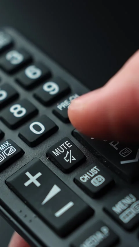 Vertical macro close-up of a finger using the P key on a TV remote to switch Stock Footage 331487602