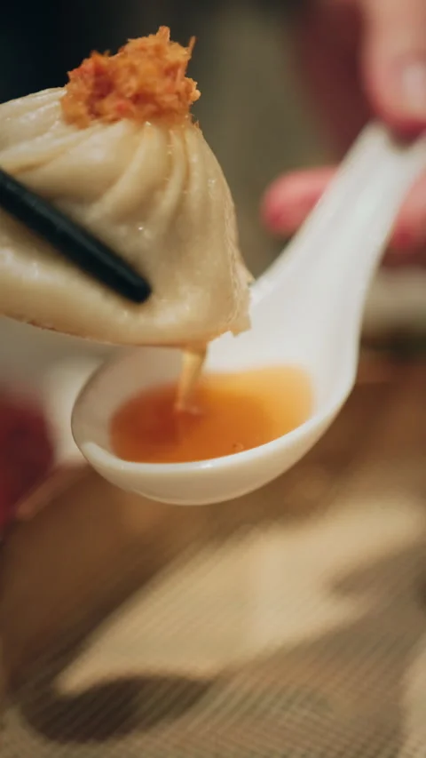 Vertical macro close-up of soup dumpling with crab roe on ceramic spoon Stock Footage 333898371