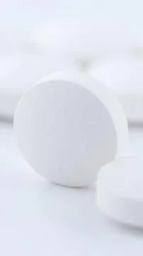 Vertical macro close up view of white round pharmaceutical tablets stacked on Stock Photos