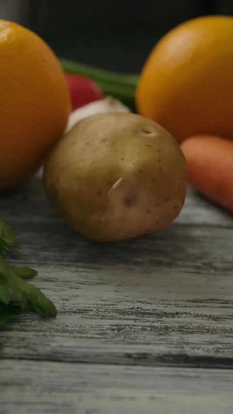 Vertical of Macro dolly plan of rolling potato on wooden table Stock Footage 276927338