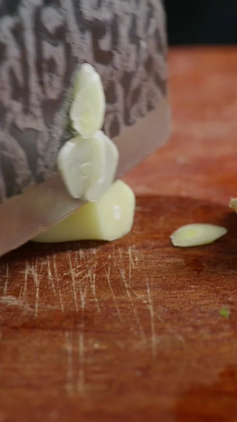 Vertical: Macro extreme close-up shot of garlic being sliced into thin flakes. Stock Footage 341837432