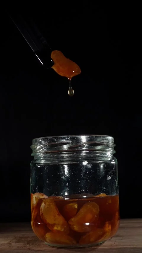 Vertical Macro Fermented Garlic Clove Dripping Honey Drop Tweezers Stock Footage 324920684