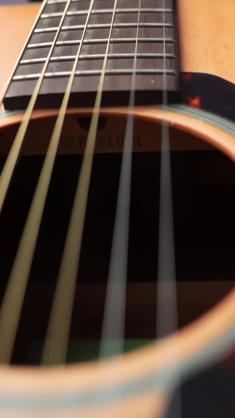 Vertical macro move up from the acoustic guitar bridge past the strings toward 스톡 동영상 329480012