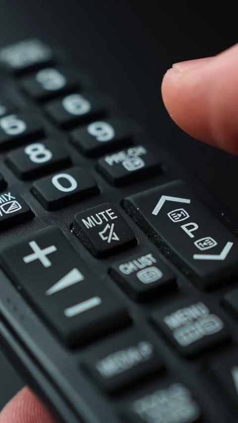 Vertical macro shot of a finger tapping the mute button on a TV remote Stock Footage 329611618