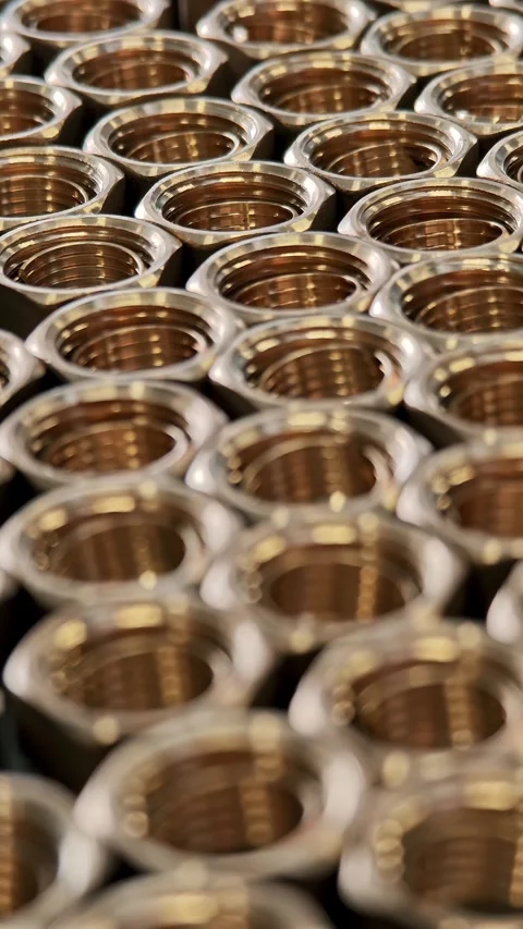 Vertical macro of threaded brass nuts. Precision metalworking and industrial Stock Footage 329289596