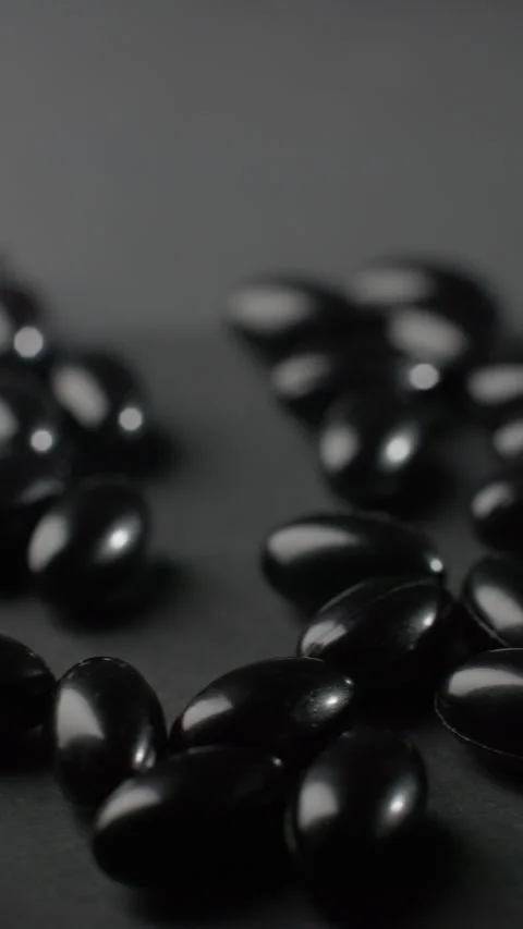 Vertical Macro Tracking Shot of Black Astaxanthin Softgels Video stock 332369525