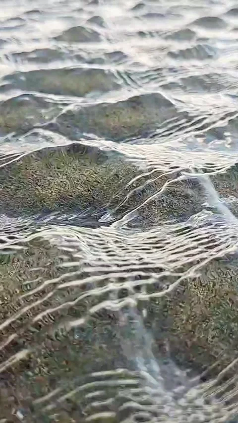 Vertical macro video of crystal clear water wave ripples on wet sand Stock Footage 340301804