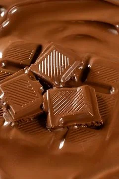 Vertical macro view of chocolate bar pieces in melted chocolate pool 写真素材