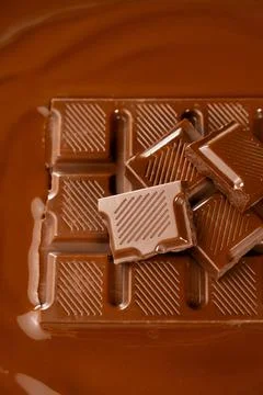 Vertical macro view of chocolate bar pieces in melted chocolate pool 写真素材