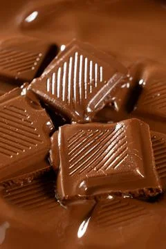 Vertical macro view of chocolate bar pieces in melted chocolate pool 写真素材