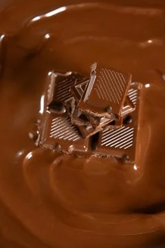 Vertical macro view of chocolate bar pieces in melted chocolate pool Stock Photos