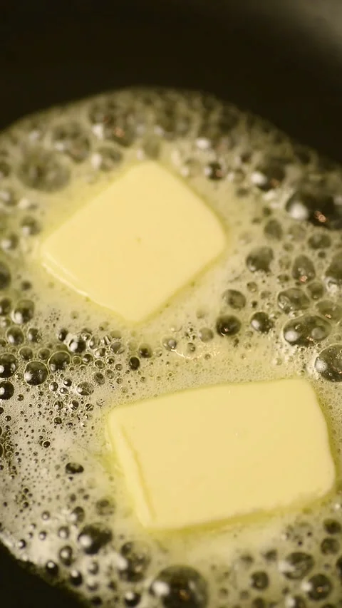 Vertical macro view of intense butter melting process on a frying pan 库存影片 344890774