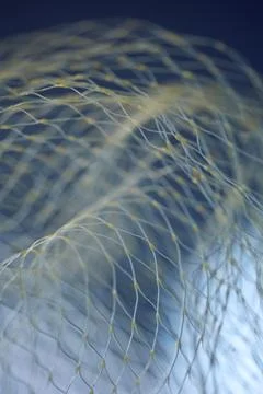 Vertical macro of yellow nylon net with selective focus on blue background. I Stock Photos