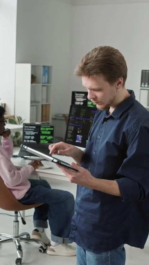 Vertical of Male App Developer Using Digital Tablet in Open Plan Office Stock Footage 330130702