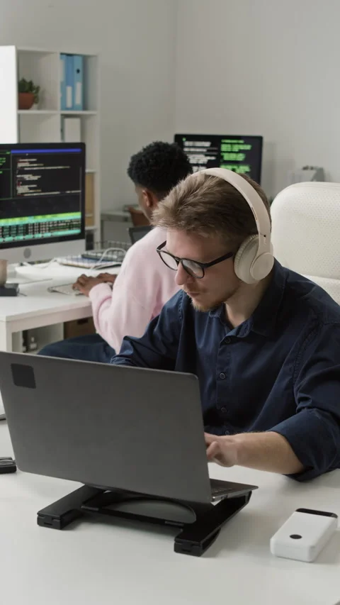 Vertical of Male Programmer in Headphones Typing on Laptop in IT Office Stock Footage 330129494