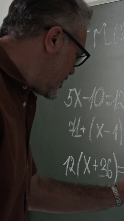 Vertical of Male Teacher Writing Math Equations on Chalkboard in Classroom Stock Footage 339652847
