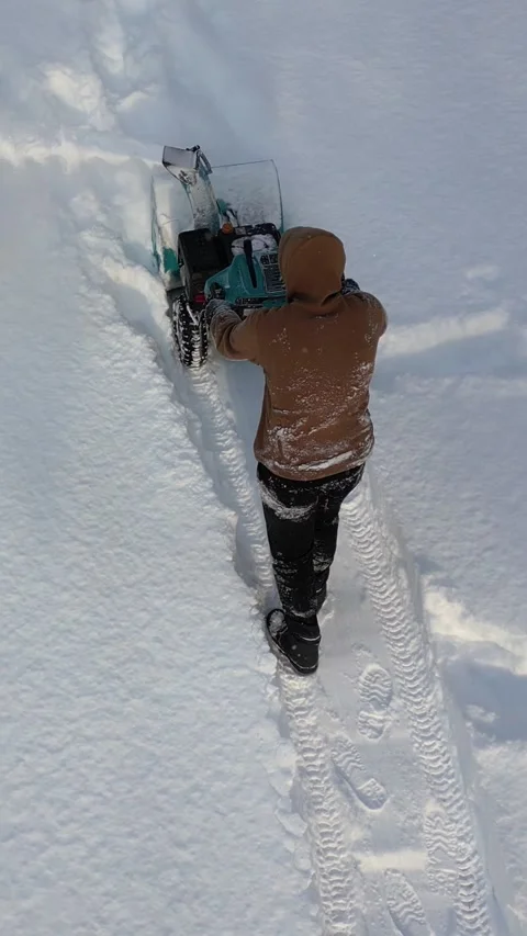 Vertical. Man dressed in winter clothes moves snow blower forward Video stock 327403229