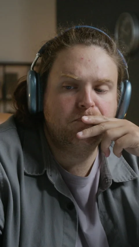 Vertical of Man in Headphones Thinking While Typing on Computer Keyboard Stock Footage 348140854