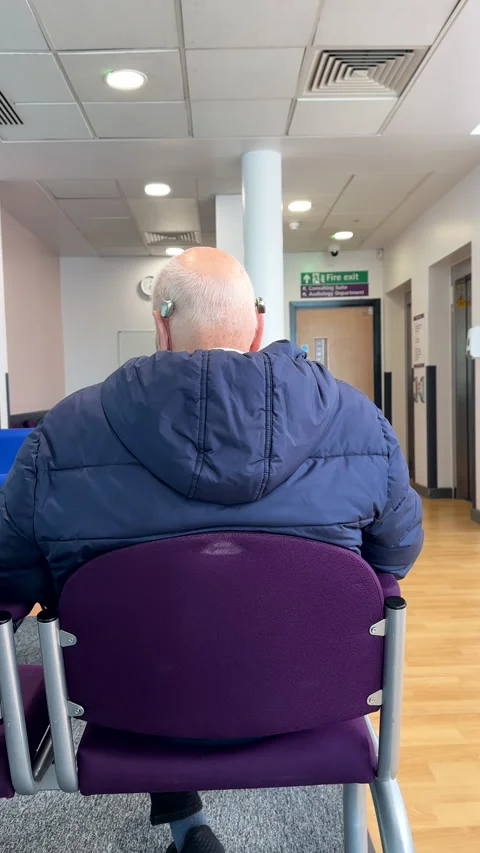 Vertical. Man with hearing aid, bone conduction implants sitting in waiting area Stock-Footage 334949990