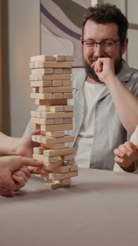 Vertical of Man Laughing and Clapping during Wooden Block Tower Game Stock Footage 340323927