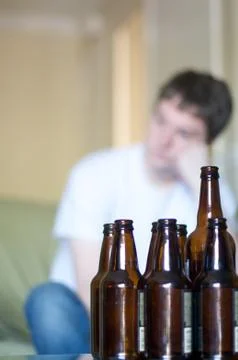 Vertical, man looking to left with empty beer bottles Stock Photos