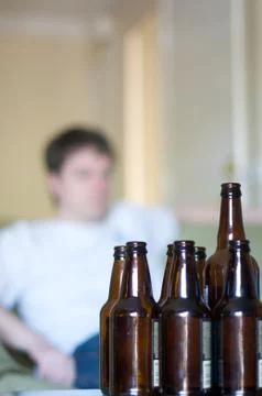 Vertical of man looking right, empty beer bottles Stock Photos
