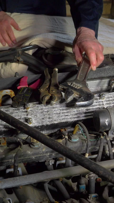 Vertical - A man preparing to start work in an old car engine bay. Video stock 280226671