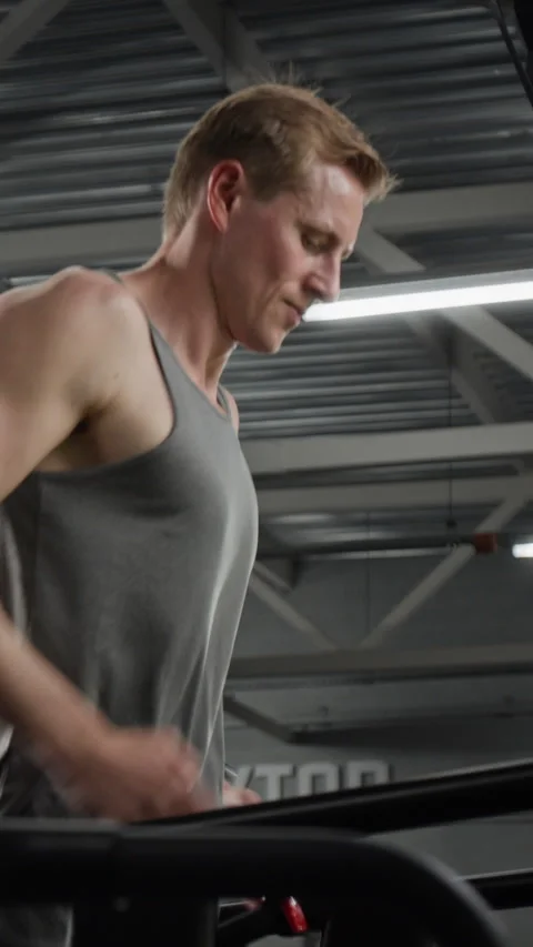 Vertical of Man Running on Treadmill during Intense Cardio Workout in Gym Stock Footage 339897154