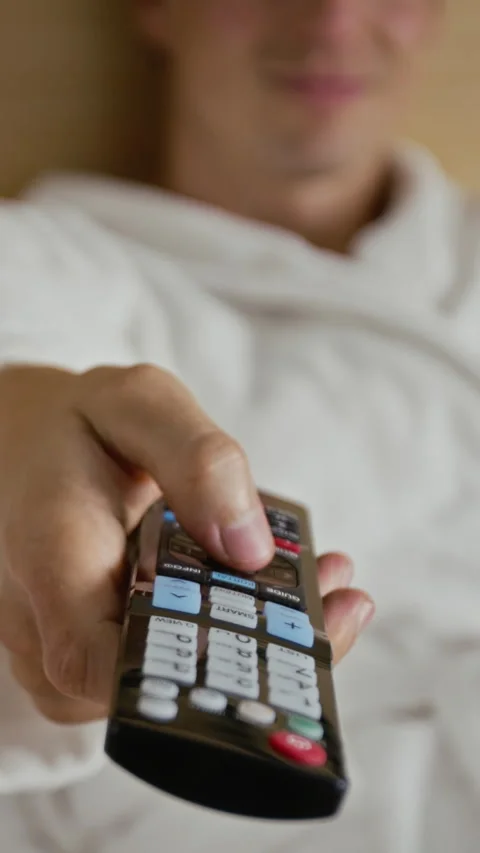 Vertical of Man Switching Channels with TV Remote Control in Bedroom Stock-Footage 345919627