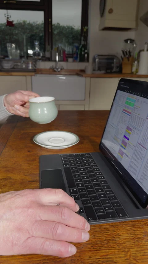 Vertical - Man at a table with a hot drink using a tablet computer and keyboard. Stock Footage 296221830