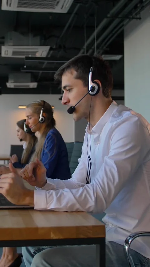 Vertical of Man using a headset while working in call-center office Stock Footage 277275391