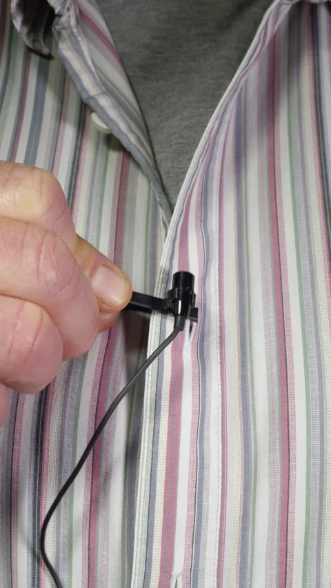 Vertical – A man's hand attaching a clip-on lavalier microphone to a shirt. Video stock 283464192