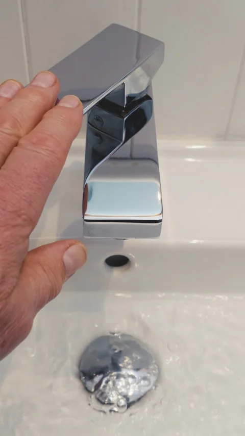 Vertical - A man’s hand pressing a sink tap lever to turn off the water flow. Stock-Footage 288338517