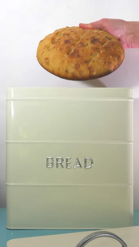 Vertical - A man’s hand removing an uncut loaf from a painted metal bread bin. Stock Footage 280229477