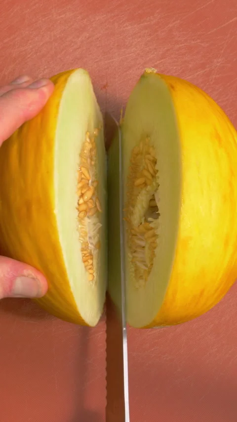 Vertical - A man’s hands using a sharp knife to slice a melon in half. Video stock 280225867