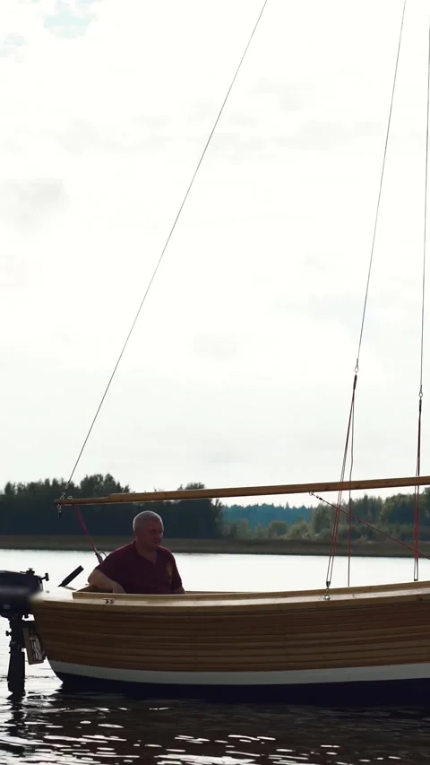 Vertical of Master and his assistant working at wood sailboat on river with mast Stock Footage 305515443