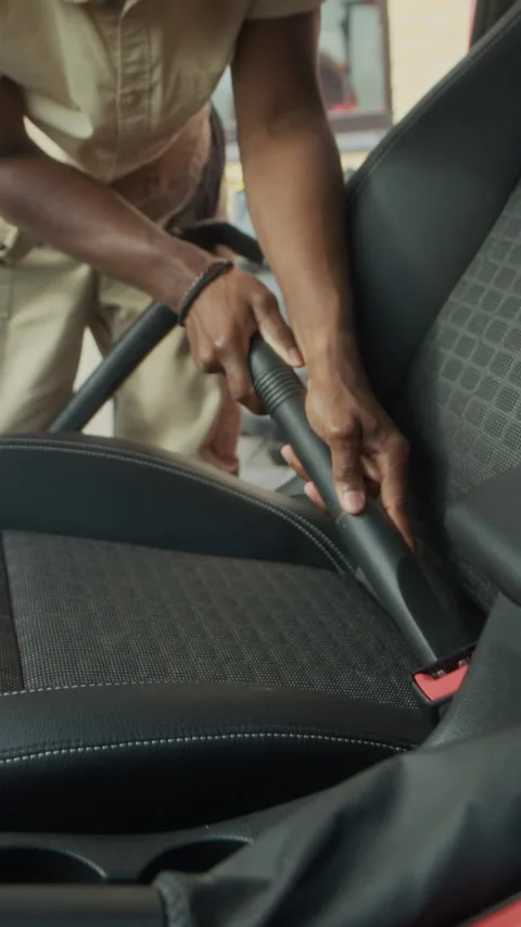 Vertical of Mechanic Cleaning Inside of Red Car Using Vacuum Hose in Garage Stock Footage 317308287