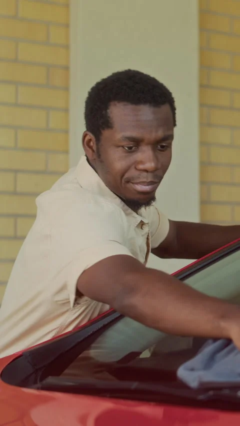 Vertical of Mechanic Wiping Down Red Car Windshield with Cloth Stock Footage 317305314