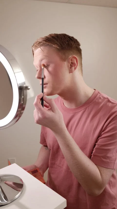 A Vertical Medium Shot of A Young Man Applying Eyeliner in Front of Mirror Stock Footage 309905819
