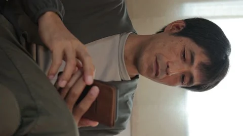 Vertical : Middle aged asian man using his smartphone at home. Stock Footage 224902551