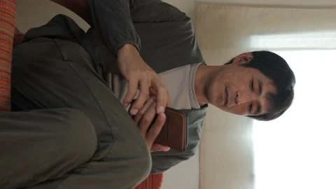 Vertical : Middle aged asian man using his smartphone at home. Stock Footage 224902614