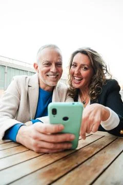 Vertical. Middle aged couple having fun sharing media with a cellphone. Mature Stock Photos