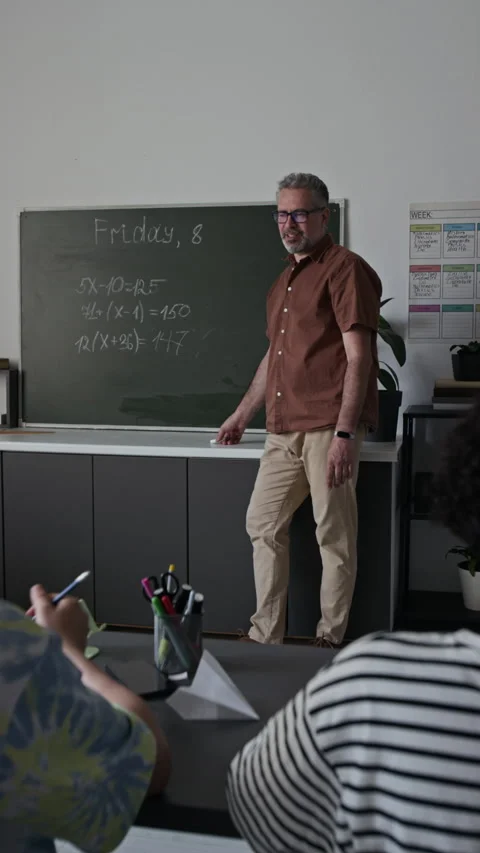 Vertical of Middle-Aged Male Teacher Explaining Math on Blackboard Stock Footage 339680452