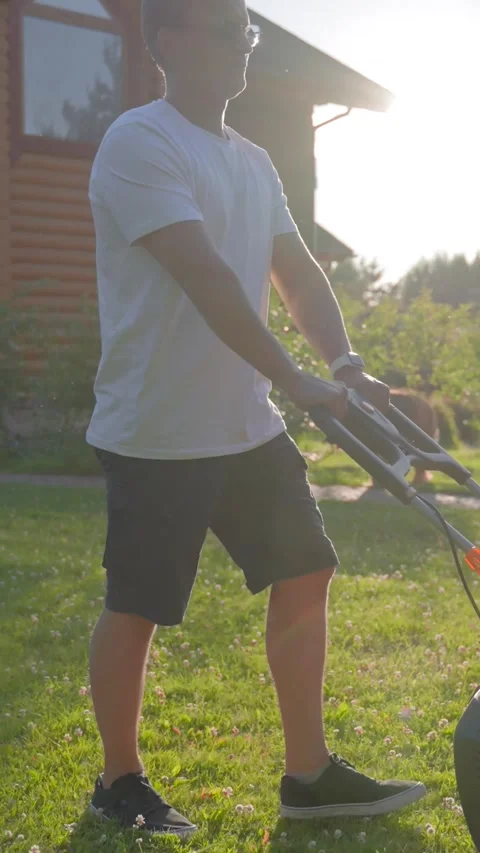 Vertical of Middle-aged man enjoys taking care of yard at back sunset Stock Footage 275623520