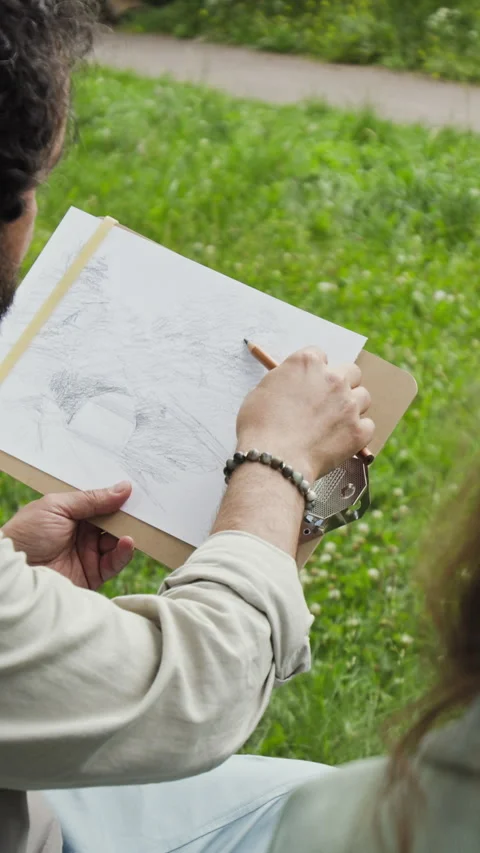 Vertical of Middle Aged Man Explaining Sketching Techniques to Woman Outdoors Stock Footage 341940955