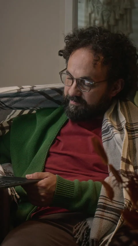 Vertical of Middle-aged Man Wrapped in Blanket Working Remotely on Laptop Stock Footage 341677490
