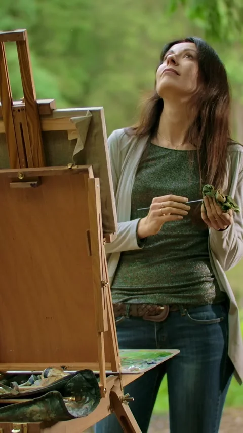 Vertical of Middle view of a beautiful brunette woman painting a picture on Stock Footage 276929787