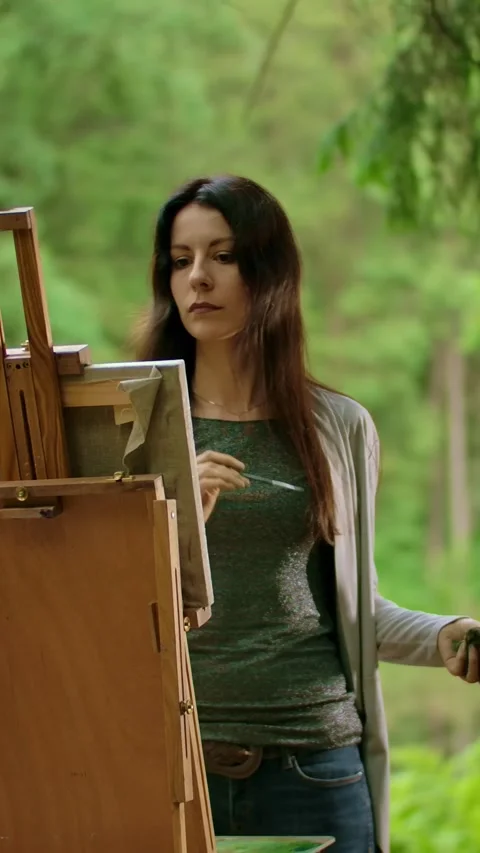 Vertical of Middle view of a beautiful brunette female painting a picture in a Stock Footage 276930965