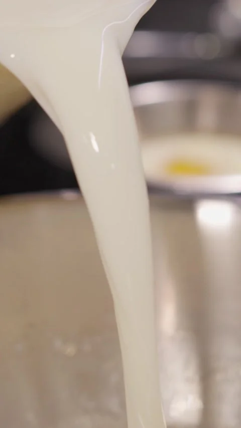 Vertical. Milk flows into sweet foamy egg mixture creating base for dough Video stock 324866723