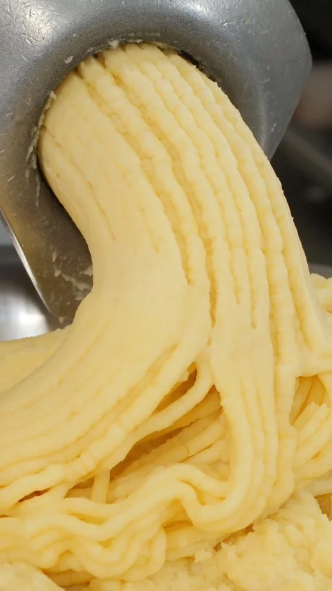 Vertical. Minced boiled potatoes slowly emerge from meat grinder in kitchen Stock-Footage 323465152
